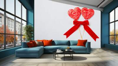 Coffee for Valentine`s day morning in white cup with two red heart lollipops and red ribbon bow on grey or blue background, copy space top view, creamy froth Wall mural